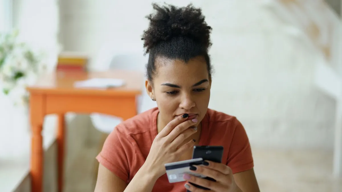Person holding a credit card and phone while checking a loan offer